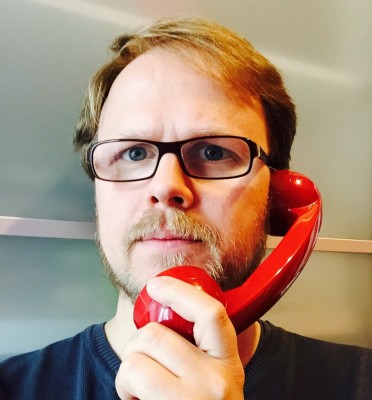 Jöran Muuß-Merholz mit einem roten Telefonhörer am Ohr